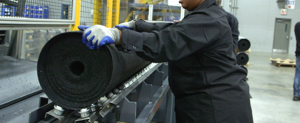 Operator at Pliteq factory rolling a GenieMat RST roll